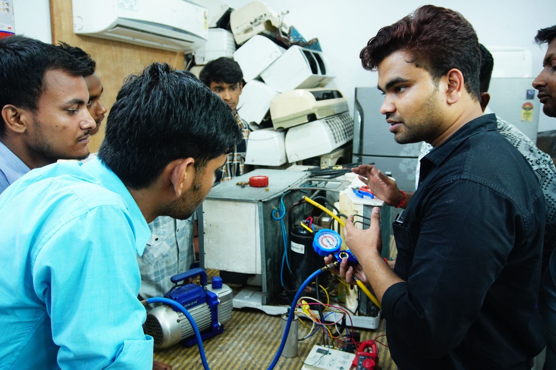 Instructor walking a group of trainees through a hands-on equipment check in a training workshop.