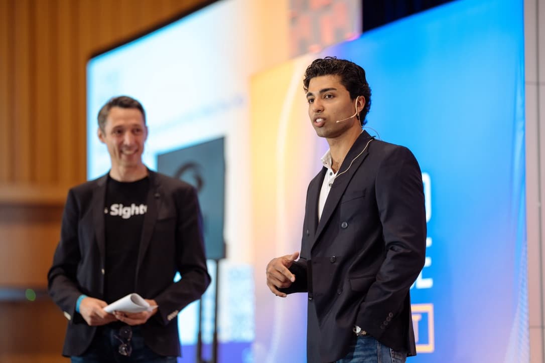 Aaryan speaking on stage with a headset microphone.