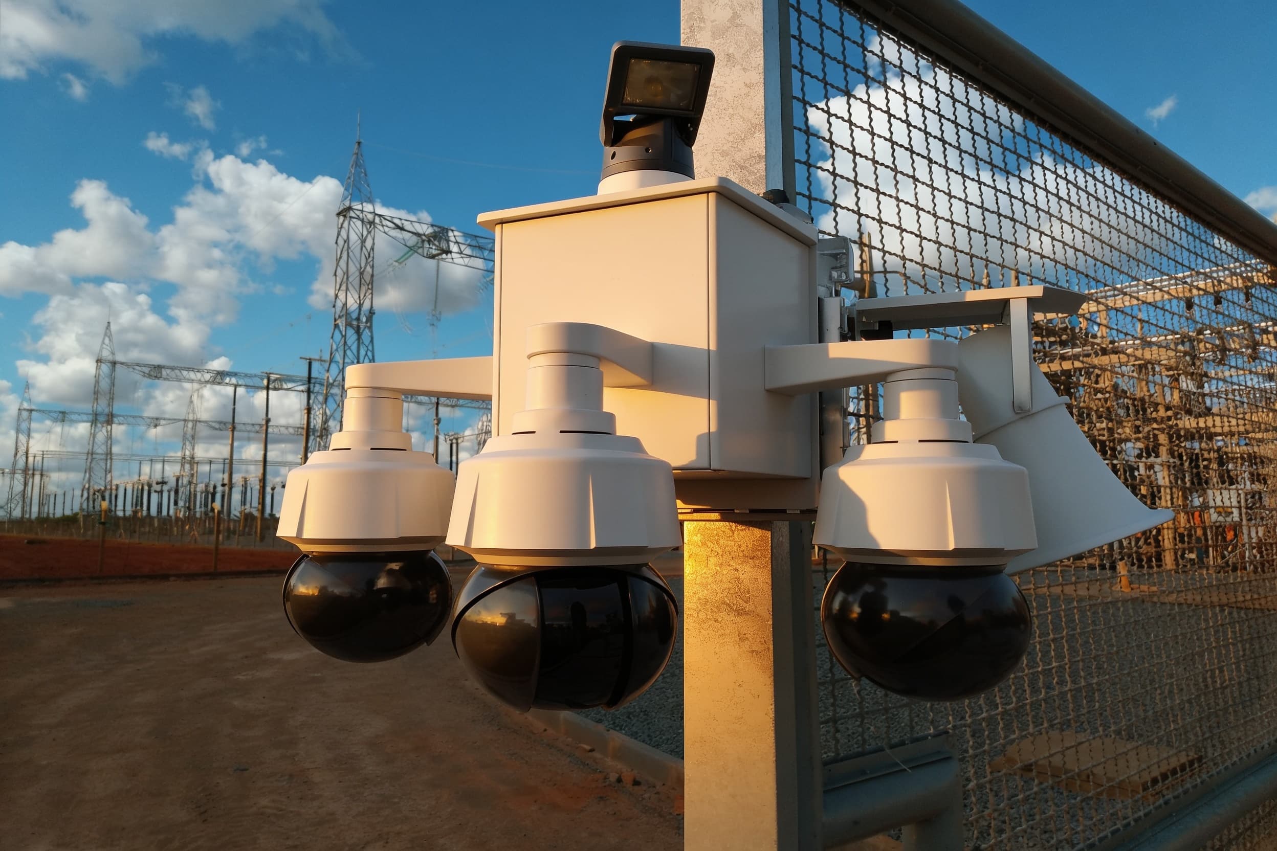 A security camera on the perimeter pole by the fence