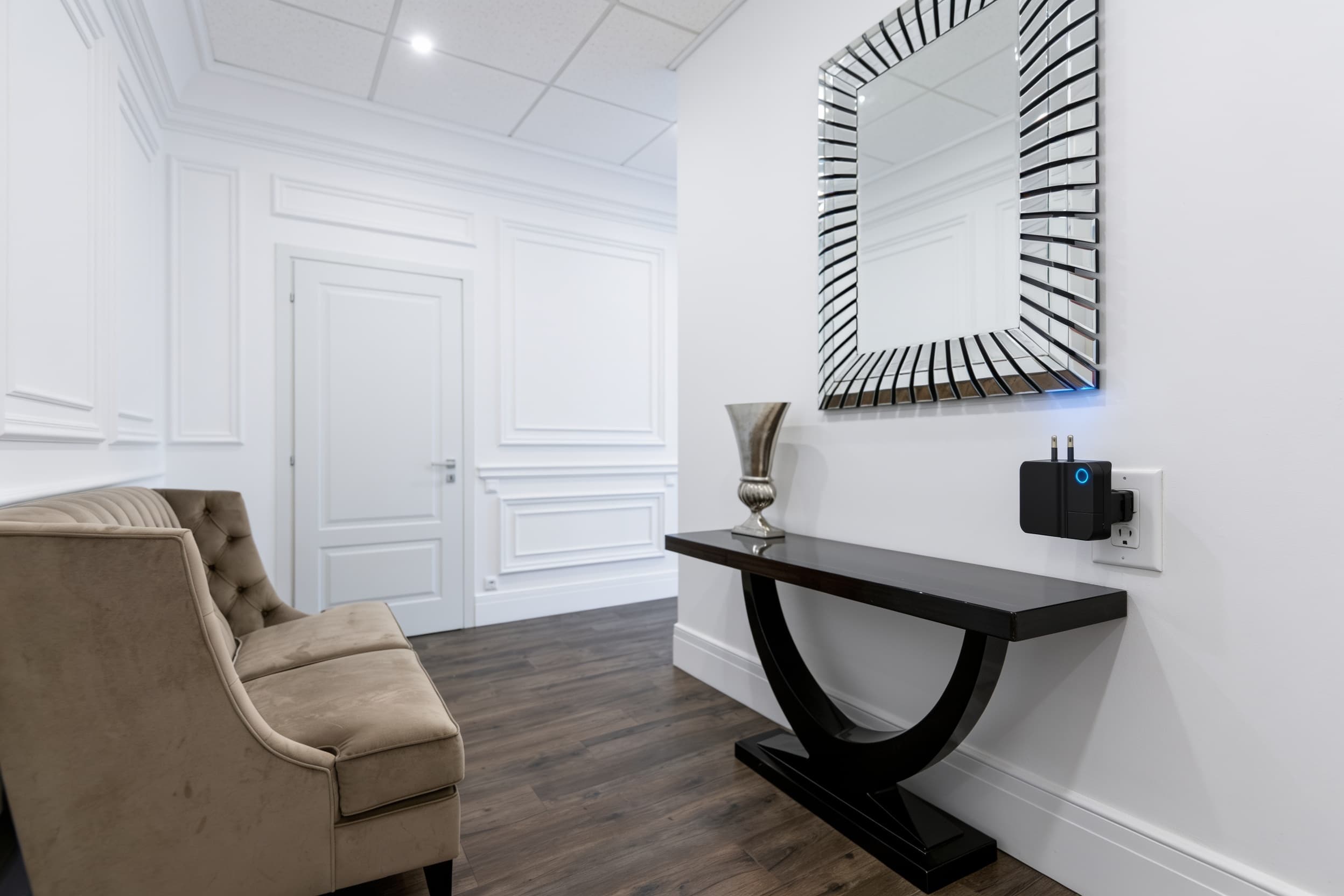 A wall-mounted security sensor plugged into the outlet above the baseboard