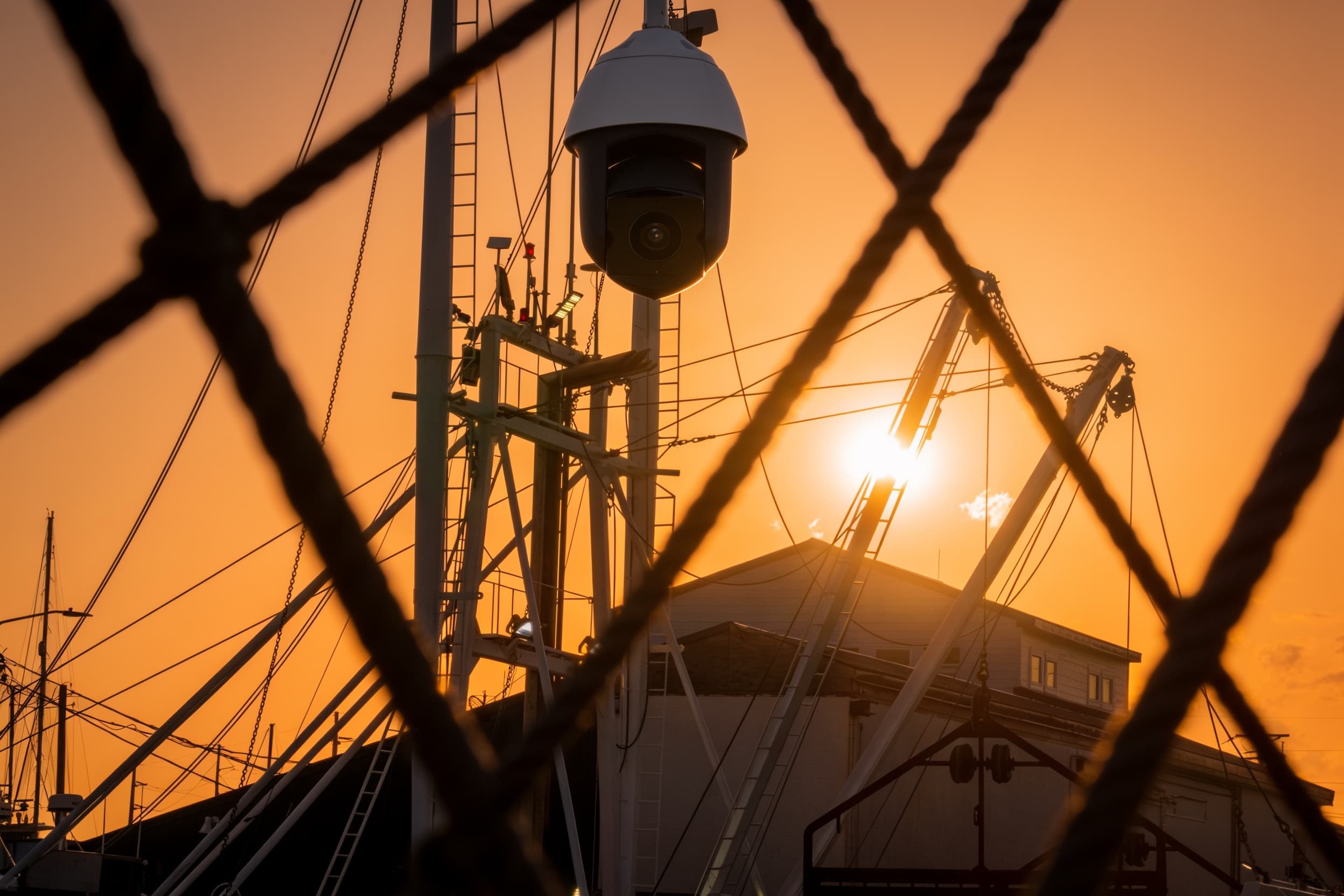 PTZ camera atop a harbor mast at sunset